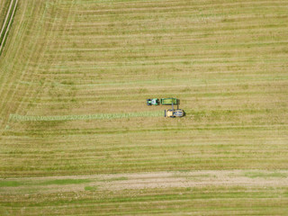 Fototapeta na wymiar Aerial view of tractor and harvester on agricultural field on warm summer day in Switzerland