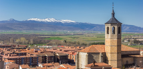Fototapeta na wymiar Panorama of church tower and snowcapped mountains near Avila, Spain
