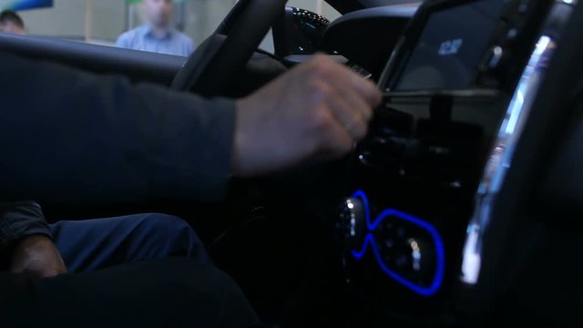 Man using large touchscreen dashboard in car, testing new vehicle functions