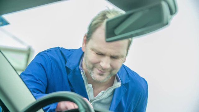 A man is annoyed when he sees the crack on the front window of the car.