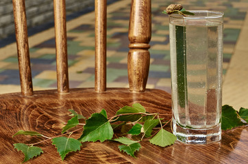Glasses of birch sap juice drink birch branches on wooden table background healthy vitamin spring useful nutrition natural fresh drink.