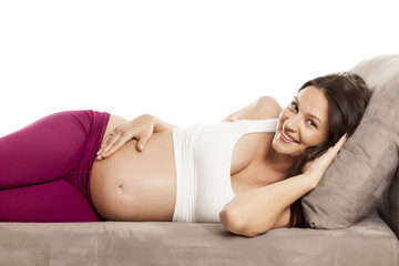 happy beautiful pregnant woman lying on a bed on the white background