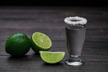 Single shot silver tequila on a black wooden background