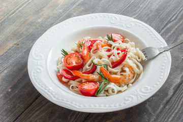 Fried shrimp with pasta, paprika and rosemary in a white plate