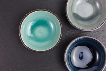 three glazed ceramic bowls on black slate plate