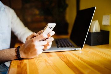 Concentrated handsome well-dressed male international student typing on laptop computer text using information from web sources while sitting in coffeeshop with wifi
