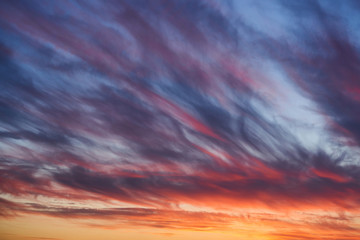 Naklejka na ściany i meble Dramatic sunset sky with clouds. Bright blue and orange sky