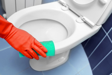 Hand wipes the toilet.