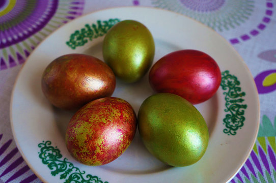 Green and red Easter eggs on a white plate with ornament