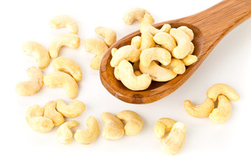 Heap of raw, organic, whole cashew nut kernels in wooden spoon on white