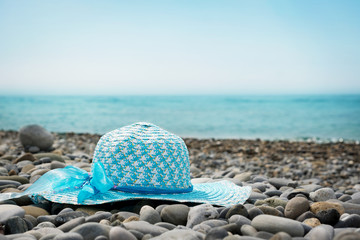 women's woven straw blue hat lies on the beach