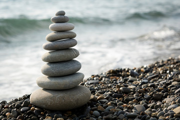 a pyramid of stones on a pebble beach on the background of the sea waves in the evening