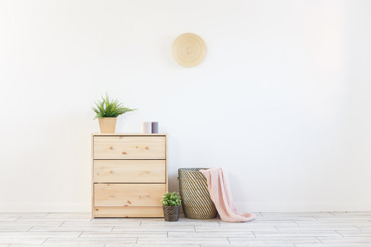 Concept of a cozy interior and housewarming - small wooden chest with accessories and laundry basket on white wall background. Copyspace
