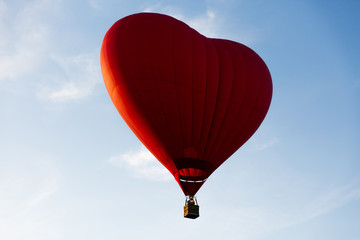 Red hot air balloon in the shape of a heart fly in sky. Love, honeymoon and romantic travel concept