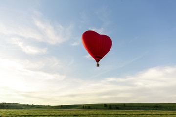 Red hot air balloon in the shape of a heart fly in sky. Love, honeymoon and romantic travel concept