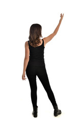 full length portrait of brunette girl wearing black singlet, jeans jeans and boots. standing pose, with back view. isolated on white studio background.