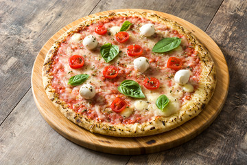 Pizza with tomatoes, cheese and basil on wooden table