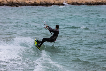 Professional Kitesurfer / Kitesurfing in the Mediterranean sea practicing with his Kiteboarding in the blue sea of the Mediterranean in the middle of winter