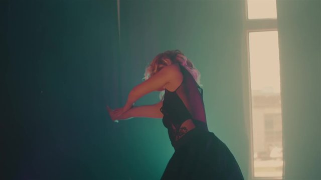 a young woman is engaged in the production of dance for her future performance on stage, a lady with curly hair is dressed in a chiffon dress, she leaned forward and froze