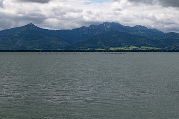 River side of a big lake in front of big mounts in bavaria under grey clouds 