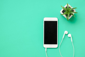 Top view of white mobile phone with headphone