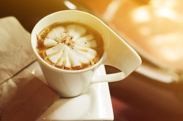 cappuccino cup in coffee shop with gradient sunlights backgrounds