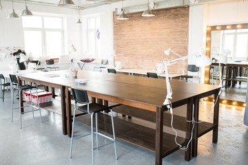 Modern atelier interior with wooden workstation in foreground and sewing dummies, no people, copy space background