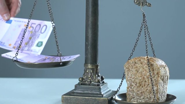 Bread outweighing euro on scales, concept of living wage, gross domestic product