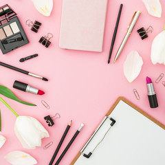 Female composition with clipboard, tulips, cosmetics and accessory on pink background. Top view. Flat lay. Home feminine desk.
