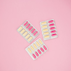 Medical composition with vitamins pills on pink background. Flat lay, top view.