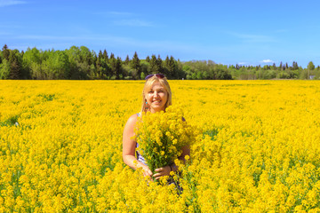 Fototapeta premium Happy blonde enjoys nature in a yellow field.