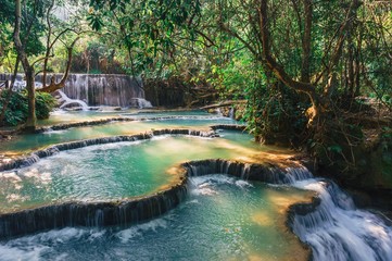 Beautiful waterfall Kuang Si in sunlight.Landscape with amazing turquoise water of Kuang Si cascade waterfall at deep tropical rain forest.Landscapes and places of rest in Laos.