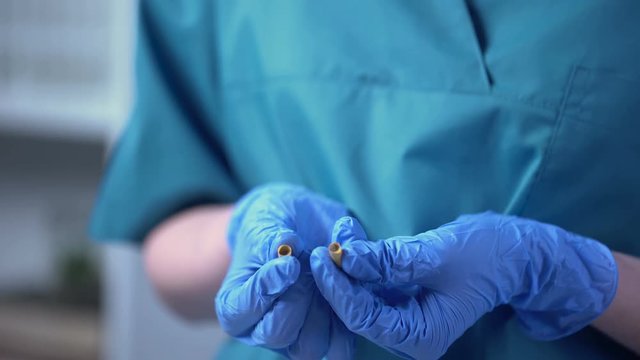 Scientist opening pill, painted chalk inside, falsification of pharmaceuticals