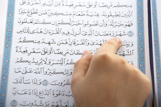 Muslim boy pointing to the word : Ramadan ( The holy Month ) while reading the Quraan in a mosque