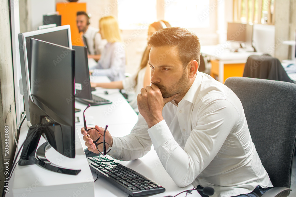 Wall mural Worried young business man working on computer at office