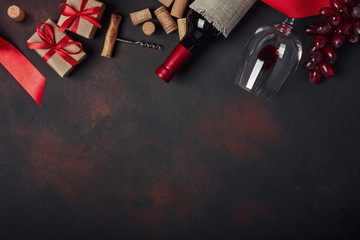 Bottle of wine, gift box, red grapes, corkscrew and corks, on rusty background