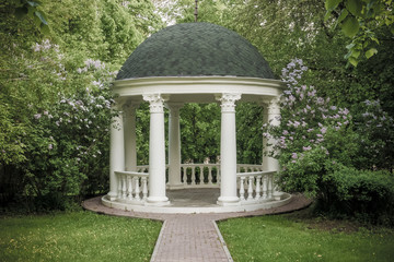 Beautiful white gazebo in a blooming spring Park