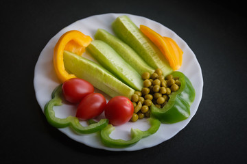 Various vegetables on a plate - cucumbers, tomatoes, paprika and pea.