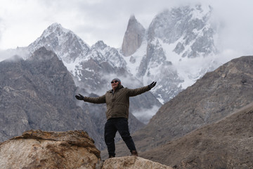 a man raising hand up on the mountain peak and Ladyfinger mountain peak background, in Pakistan