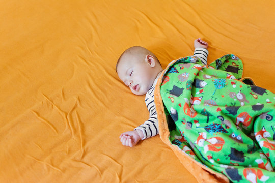 Cute Baby Sleeping On Big Bed Covered With Soft Fleece Blanket. High Angle View, No Retouch, Natural Light.