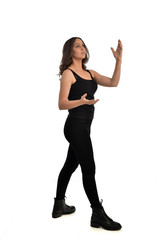 Fototapeta na wymiar full length portrait of brunette girl wearing black singlet, jeans jeans and boots. standing pose, isolated on white studio background.