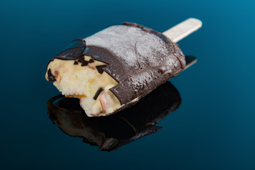 chocolate outer popsicle and beans inside with some bites on a blue background close up