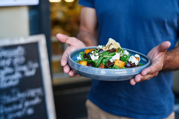 Man holding a delicious salad plate at a bistro