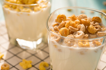 side view two cups of milk with cereal rings in a sunny morning as healthy breakfast
