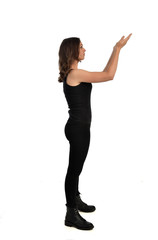  full length portrait of brunette girl wearing black singlet, jeans jeans and boots. standing pose, isolated on white studio background.