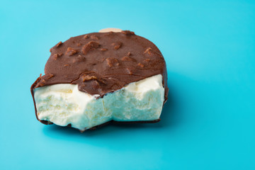 side view chocolate outer ice cream with some bites on a blue background close up