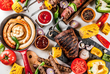 Assortment various barbecue food grill meat, bbq party fest - shish kebab, sausages, grilled meat fillet, fresh vegetables, sauces, spices, white marble background, above copy space