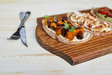 Assorted open faced sandwiches sitting with cutlery on a table