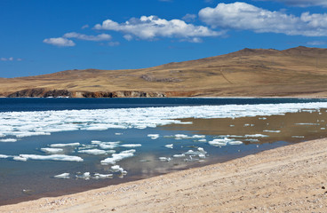 Fototapeta na wymiar Lake Baikal in May sunny day. In the shallow bays of Olkhon Island, the last ice floes melt. Season change. Spring bright landscape