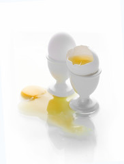 eggs on a stand with a spilled yolk on a white background
